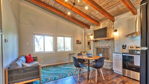 A modern kitchen with a stone fireplace, wooden beams, and a dining area with a colorful rug. - Quaint Cottages in Canyon Lake! Perfect for kids! (Canyon Lake)