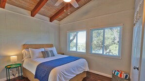 Un dormitorio con cama, mesita de noche, ventana y puerta.