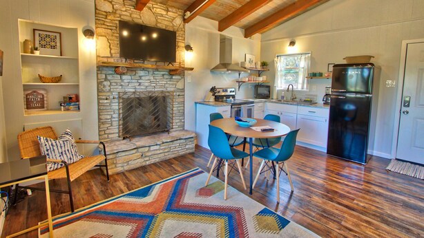 Una cocina amplia con chimenea de piedra, electrodomésticos modernos y un comedor con sillas azules.