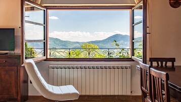 A room with a large window, a white chair, a radiator, and a wooden table.