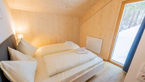 A wooden cabin bedroom with a bed, pillows, and a window. - Woody 21 - the Tiger Woody (St. Georgen am Kreischberg)