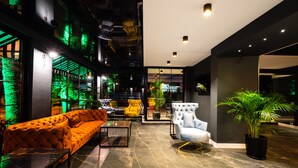 A modern lobby with a sofa, armchairs, and a potted plant.