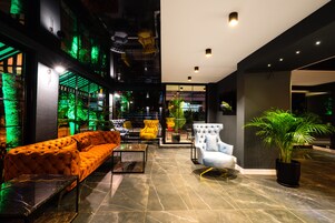 Un vestíbulo moderno con un sofá, sillones y una planta en maceta.