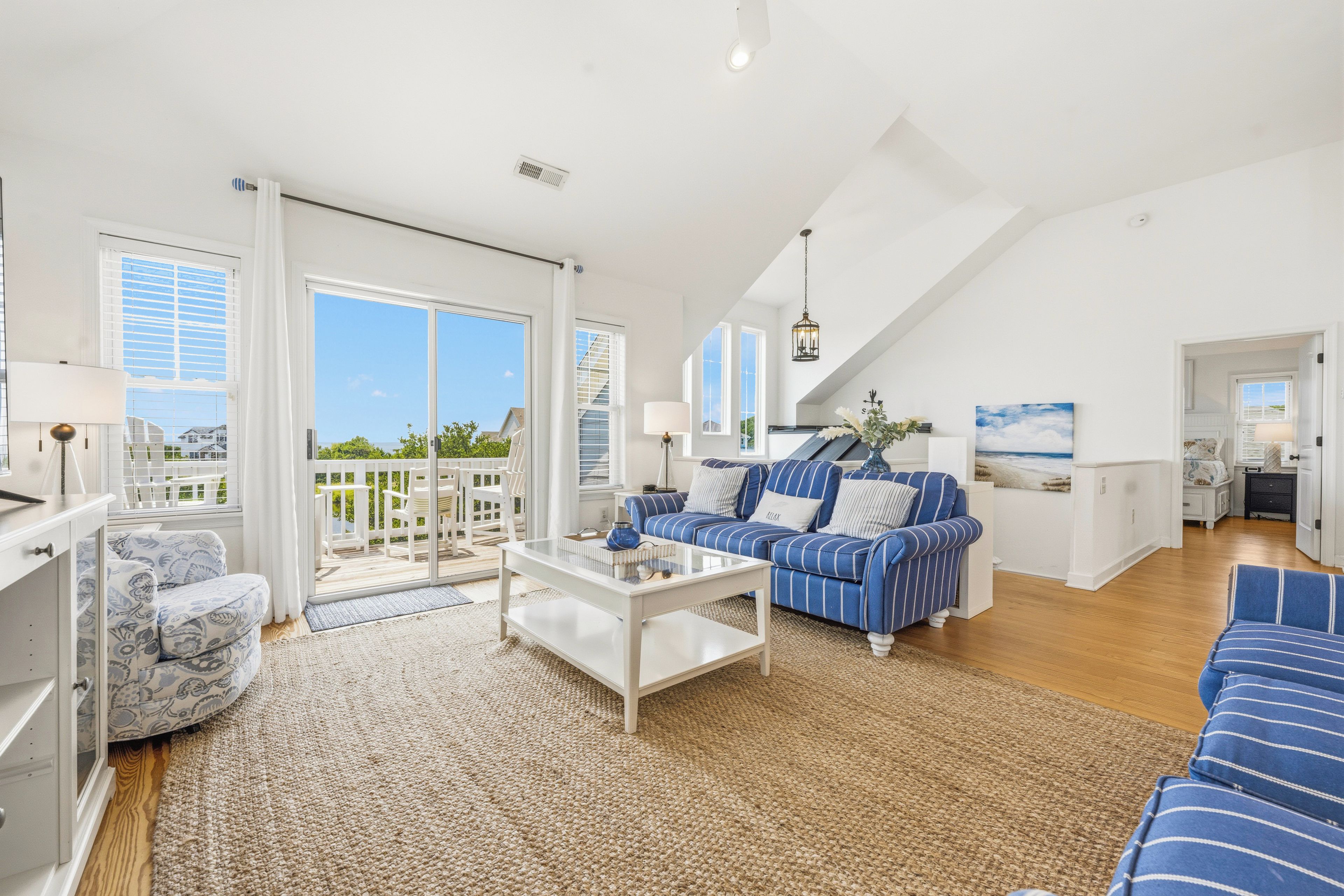 A spacious living area with a large sofa, a coffee table, and a view of the outdoors through a sliding glass door.