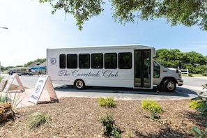 A white bus with "The Currituck Club" written on the side parked on a street. - Calypso: Private Pool, Hot Tub, 6 Bedrooms (Corolla)