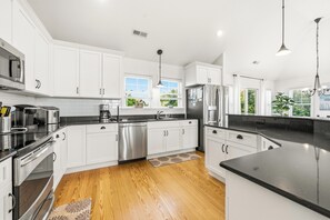 Una cocina moderna con armarios blancos, electrodomésticos de acero inoxidable y encimera negra.