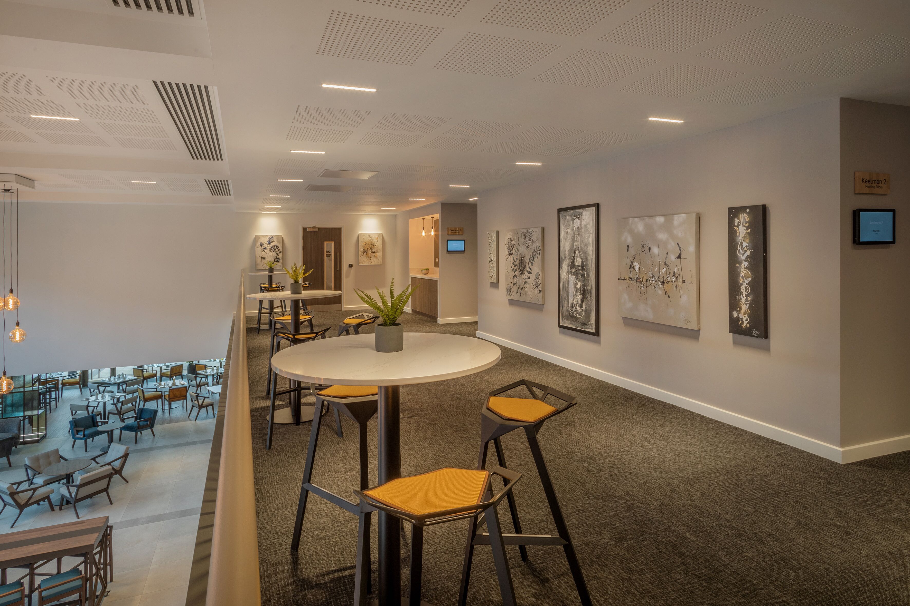 A modern interior with a round table, bar stools, and artwork on the walls.