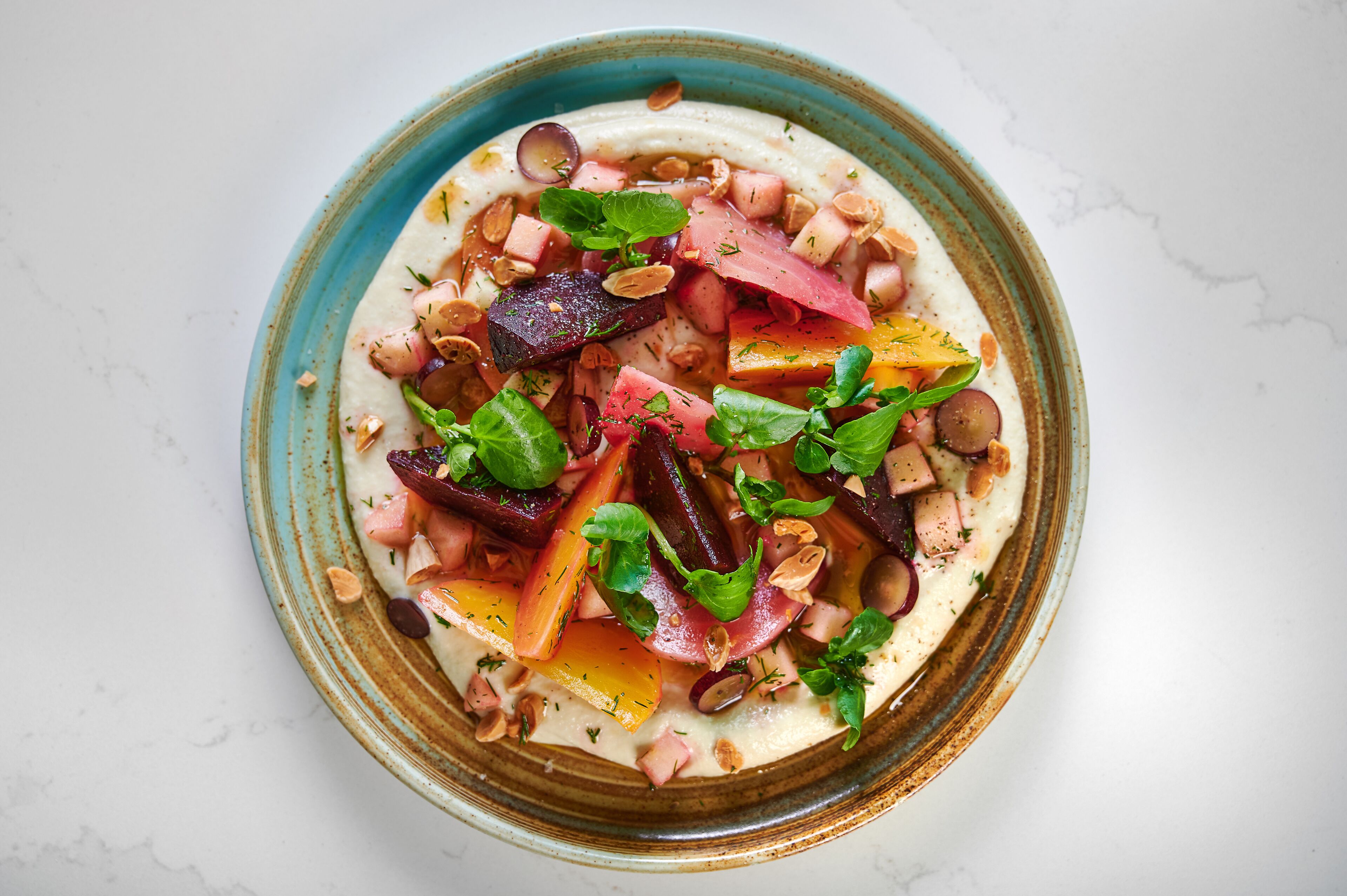A bowl of food with various vegetables and nuts.