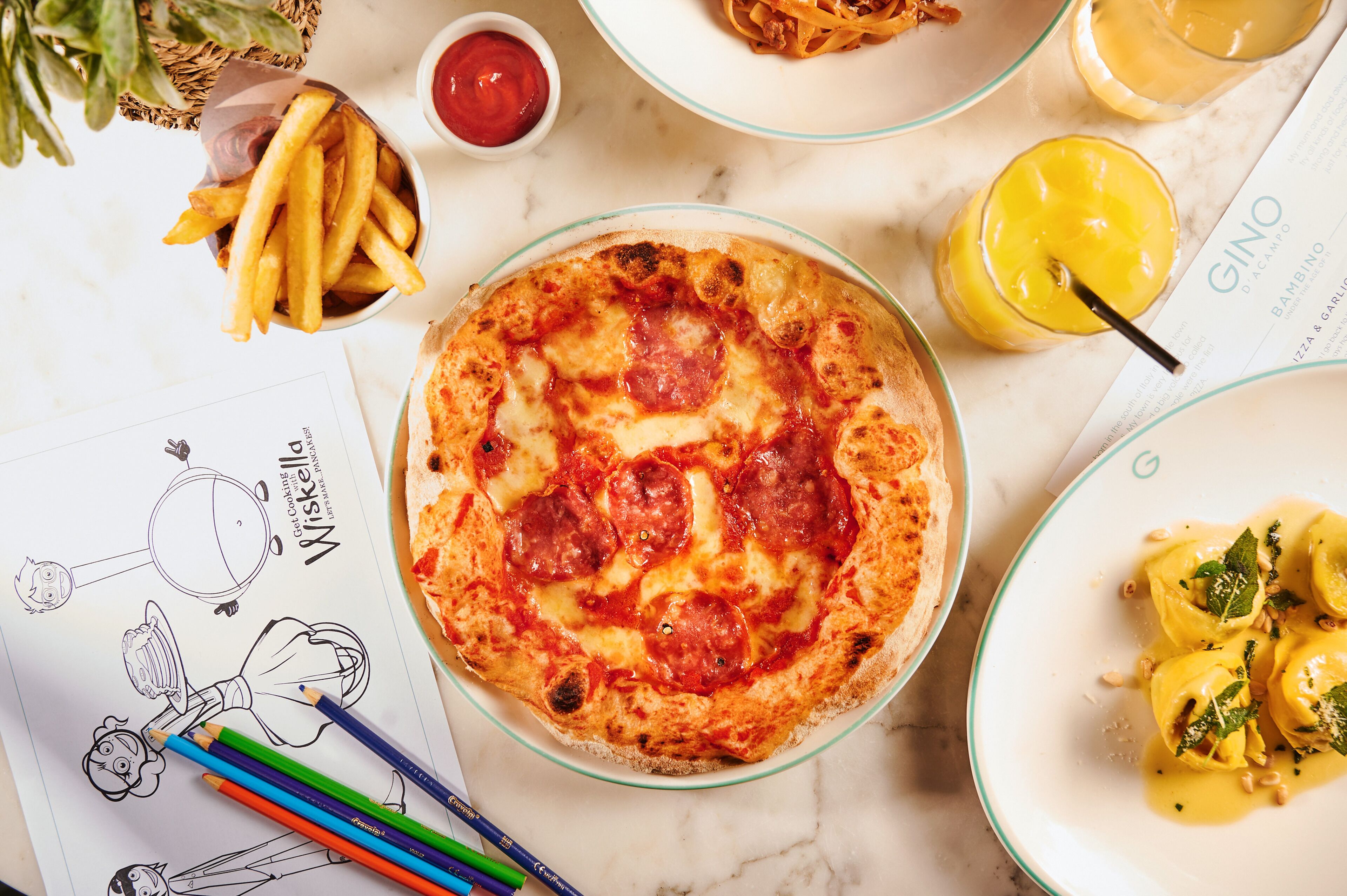 A pizza with pepperoni, a plate of ravioli, a basket of fries, and a menu.