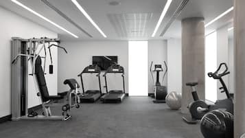 Un gimnasio moderno con cintas de correr, elípticas y pesas sueltas.