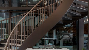 Eine moderne Wendeltreppe mit minimalistischem Design, einer zentralen Plattform und hängenden, kugelförmigen Leuchten.
