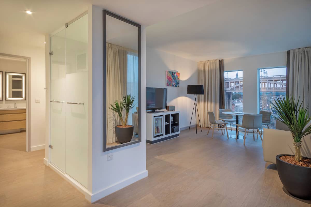 Un salon moderne avec une cloison en verre, un coin repas et une vue sur le paysage urbain.