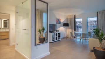 A modern living room with a glass partition, a dining area, and a view of a cityscape.