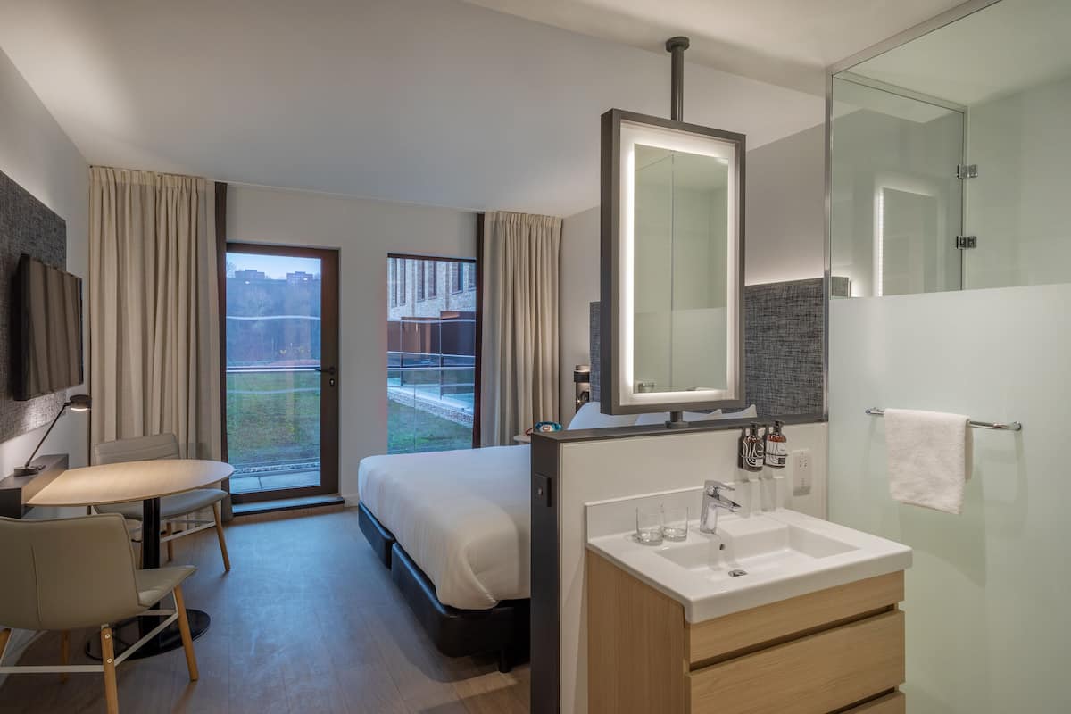 Une chambre d’hôtel moderne équipée d’un lit, d’un bureau et d’une salle de bain.