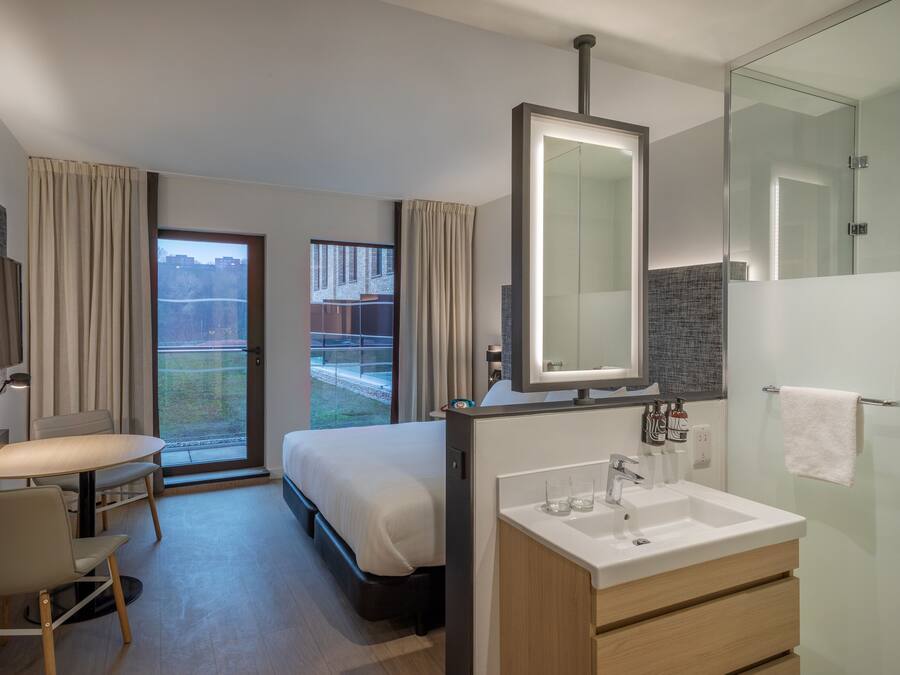 A modern hotel room with a bed, desk, and bathroom.