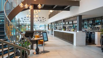 Un intérieur moderne avec un escalier en colimaçon, un coin bar et des espaces aménagés pour s’asseoir.