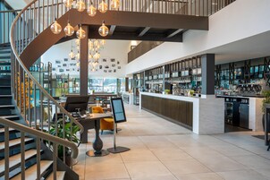 A modern interior with a spiral staircase, a bar area, and seating arrangements.