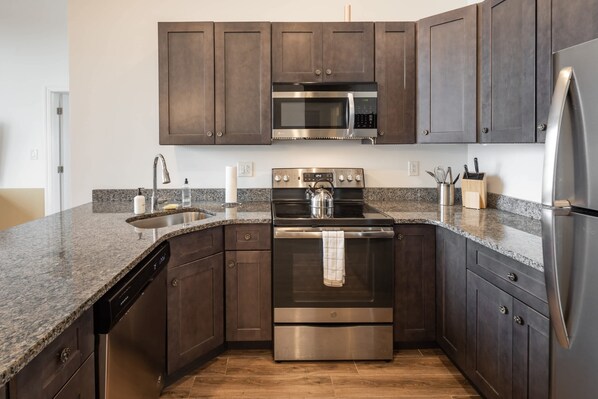 A modern kitchen with dark wooden cabinets, stainless steel appliances, and a granite countertop.