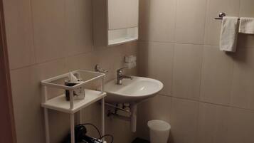A modern bathroom with a white sink, mirror, and storage shelves.