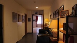 Um corredor com sofá, luminária e quadros nas paredes.