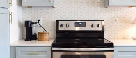 Una cocina con estufa, horno de acero inoxidable y un salpicadero con diseño hexagonal.