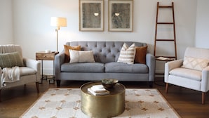 A living room with a grey sofa, two framed artworks, a floor lamp, a coffee table, and a ladder against the wall. - Home on the Range (Cookeville)