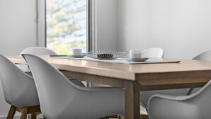 Een eettafel met stoelen, een witte kom en een beker.