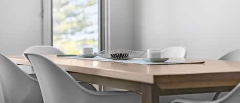 Una mesa de comedor con sillas, un tazón blanco y una taza.