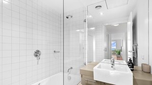 Een moderne badkamer met een douchecabine van glas, een wastafel met twee kommen en een grote spiegel.