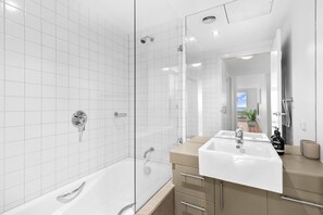 A modern bathroom with a glass-enclosed shower, a double sink vanity, and a large mirror.