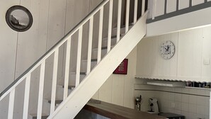 Een keuken met een houten trap, een betegelde achterwand en een klok aan de muur.