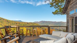 A wooden deck with wicker furniture and a view of mountains. - Sky High at Laurel Ridge | Post & Beam Cabin With Long-range Mountain Views! (Black Mountain)