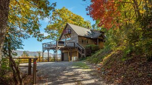 A cabin with a wooden exterior, a deck, and a staircase leading to a second level. - Sky High at Laurel Ridge | Post & Beam Cabin With Long-range Mountain Views! (Black Mountain)