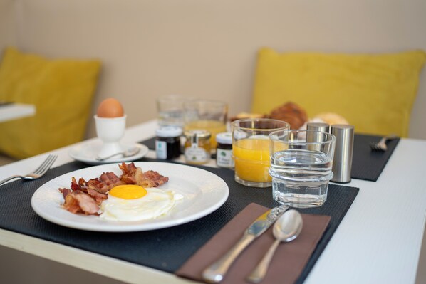 A breakfast table with a plate of bacon and egg, a glass of orange juice, and a bottle of jam. - Le Boutique Hotel (Rome)