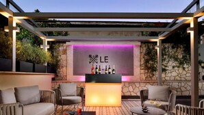 An outdoor bar area with a stone wall backdrop, a bar counter, and seating arrangements. - Le Boutique Hotel (Rome)