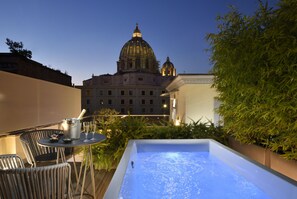 A rooftop terrace with a hot tub, outdoor seating, and a view of a large building with a dome. - Le Boutique Hotel (Rome)