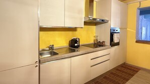A kitchen with white cabinets, a stainless steel sink, a built-in oven, and a window with a view.
