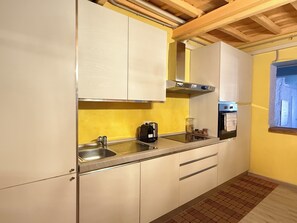 A kitchen with white cabinets, a stainless steel sink, a built-in oven, and a window with a view.