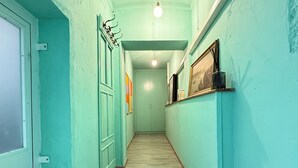 A hallway with teal walls, wooden flooring, and a door on the left.