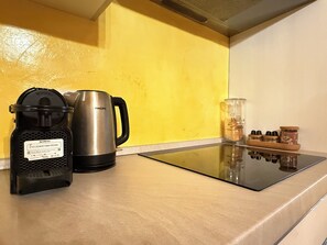 A kitchen counter with a coffee maker, a kettle, and a glass jar with biscuits.