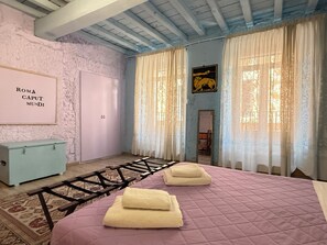 A bedroom with a bed, a chest of drawers, a framed picture on the wall, and a door.