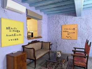 A room with a sofa, armchair, and a small table with a vase. There are two motivational posters on the walls.
