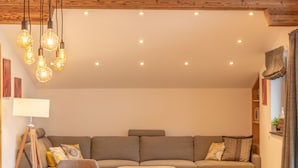 A cozy living room with a sofa, a wooden dining table, and pendant lighting. - FINEST VILLA Zell am See, luxury, sauna, 12 pax (Zell am See)