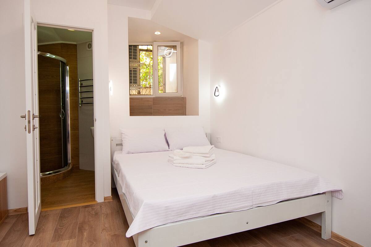 Un dormitorio con cama, ventana y puerta que da al baño.