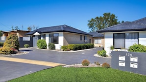 A modern residential building with a driveway, numbered units, and well-maintained landscaping. - Villa Zelma - Pet Friendly - 4 Min Walk to Beach (Culburra Beach)