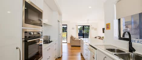 Une cuisine moderne avec des meubles blancs, des appareils en acier inoxydable et un plancher en bois.