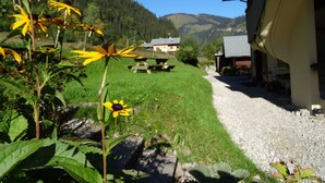 A rural setting with a building, a gravel path, and a grassy area with flowers. - Apartment for 20 people with Wi-Fi, near Linga gondola - Chatel Reservation (châtel)