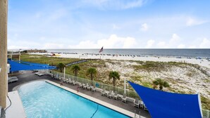 A pool area with a view of the beach and ocean.