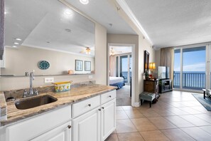 A modern kitchen with a marble countertop, a sink, and a large mirror.