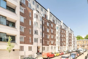 Une rangée d’immeubles résidentiels à plusieurs étages, avec un espace de stationnement devant.